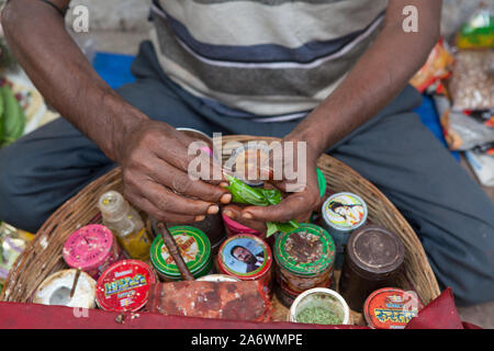 Détail d'un vendeur paan la préparation d'un mélange de tabac et d'arec enveloppée dans une feuille de bétel, Delhi, Inde Banque D'Images