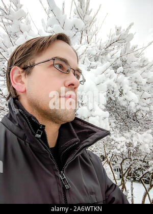 Jeune homme marchant à travers un paysage hivernal Banque D'Images