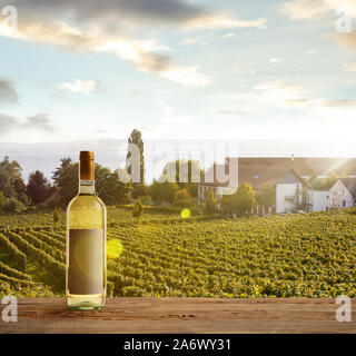 Bouteille de vin blanc sur la rampe en bois avec scène rurale du pays en arrière-plan. Feuilles vert et calme le soleil d'été 24. Copyspace. Des boissons d'alcool sur l'arrière-cour de grande maison. Banque D'Images