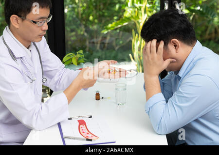 Doctor holding medicine pills in hand et expliqué avec un assortiment de médicaments médecine pharmaceutique comprimés sur la table Banque D'Images