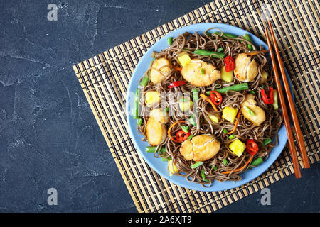 La mangue Poulet et nouilles soba avec salade de haricots verts cuits à la vapeur, carottes râpées, les poivrons et oignons de printemps sur une plaque sur une table en béton avec c Banque D'Images