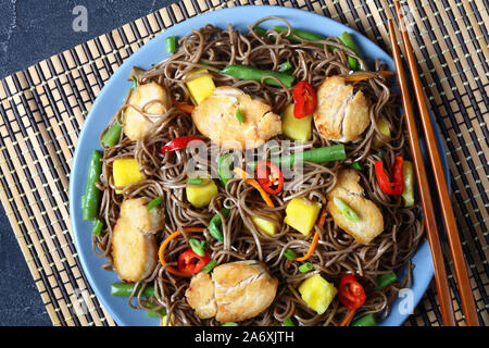 Close-up de poulet et de mangue salade de nouilles soba avec haricots verts cuits à la vapeur, carottes râpées, les poivrons et oignons de printemps sur une plaque sur un t Banque D'Images