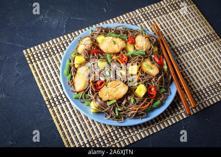 Close-up de poulet et de mangue salade de nouilles soba avec haricots verts cuits à la vapeur, carottes râpées, les poivrons et oignons de printemps sur une plaque sur un t Banque D'Images