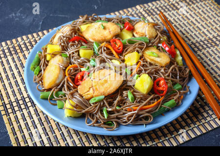 Close-up de poulet et de mangue salade de nouilles soba avec haricots verts cuits à la vapeur, carottes râpées, les poivrons et oignons de printemps sur une plaque sur un t Banque D'Images