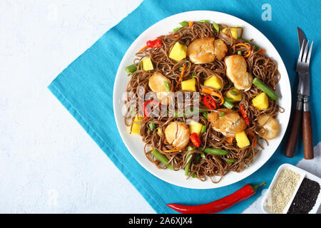 Close-up de poulet et de mangue salade de nouilles soba avec haricots verts cuits à la vapeur, carottes râpées, les poivrons et oignons de printemps sur une plaque sur un t Banque D'Images