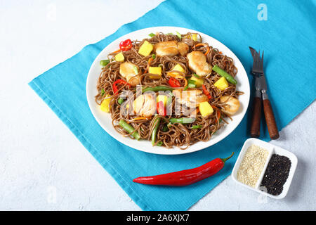 Close-up de poulet et de mangue salade de nouilles soba avec haricots verts cuits à la vapeur, carottes râpées, les poivrons et oignons de printemps sur une plaque sur un t Banque D'Images