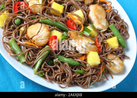 Close-up de poulet et de mangue salade de nouilles soba avec haricots verts cuits à la vapeur, carottes râpées, les poivrons et oignons de printemps sur une plaque sur un t Banque D'Images