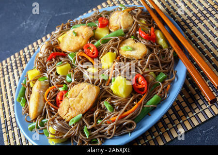 Close-up de poulet et de mangue salade de nouilles soba avec haricots verts cuits à la vapeur, carottes râpées, les poivrons et oignons de printemps sur une plaque sur un t Banque D'Images