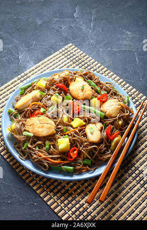 Close-up de poulet et de mangue salade de nouilles soba avec haricots verts cuits à la vapeur, carottes râpées, les poivrons et oignons de printemps sur une plaque sur un t Banque D'Images