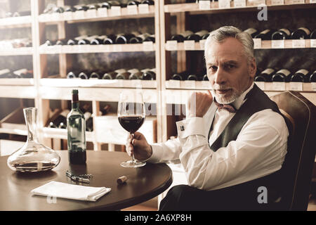 Sommelier Concept. Senior avec verre de vin à la curiosité de l'appareil photo Banque D'Images
