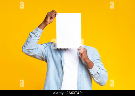 Guy noir couvrant son visage avec du papier blanc vide Banque D'Images