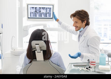 Handsome cheerful dentiste médecin démontrant son patient les résultats radiologiques Banque D'Images