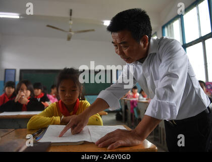 Jiangxi, Chine. 28 Oct, 2019. Huang Xinglai (R) tuteurs étudiant à l'école primaire de Huping Cunli Township dans Le'un pays de l'est de la Chine, la Province du Jiangxi, le 28 octobre 2019. Huang Xinglai, 61, utilisé pour être un professeur à l'école primaire d'Wanchong Anli Township et a pris sa retraite en juillet 2018. Il est allé à l'école primaire de Huping Cunli Township et a travaillé comme enseignant en milieu rural à nouveau en janvier de 2019 de répondre à l'appel du gouvernement local. Afin de se concentrer sur l'enseignement, Huang vit à l'école avec d'autres jeunes enseignants. Source : Xinhua/Alamy Live News Banque D'Images