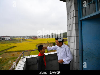 Jiangxi, Chine. 28 Oct, 2019. Huang Xinglai (R) parle avec un étudiant de l'école primaire de Huping Cunli Township dans Le'un pays de l'est de la Chine, la Province du Jiangxi, le 28 octobre 2019. Huang Xinglai, 61, utilisé pour être un professeur à l'école primaire d'Wanchong Anli Township et a pris sa retraite en juillet 2018. Il est allé à l'école primaire de Huping Cunli Township et a travaillé comme enseignant en milieu rural à nouveau en janvier de 2019 de répondre à l'appel du gouvernement local. Afin de se concentrer sur l'enseignement, Huang vit à l'école avec d'autres jeunes enseignants. Source : Xinhua/Alamy Live News Banque D'Images