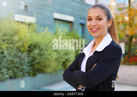 Smiling business woman looks at camera avec bras croisés à l'extérieur. Banque D'Images