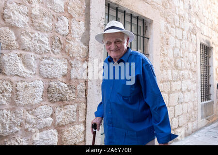 Un homme plus âgé sur son chemin à la maison de shopping s'arrête pour poser pour une photo. Dans la vieille ville de Dubrovnik en Croatie. Banque D'Images