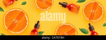 La composition de base de la création de la vitamine C, avec des tranches d'orange, une bouteille avec du sérum sur un fond jaune. Mise à plat Banque D'Images