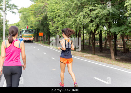 Les femmes sur la voie de jogging dans le parc tout en écoutant de la musique sur téléphone mobile. Banque D'Images