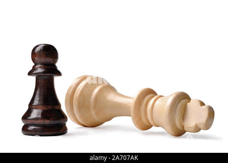 David et Goliath dans le syndrome d'échecs avec un petit pion noir debout sur une triomphante fallen king en bois clair sur un fond blanc Banque D'Images