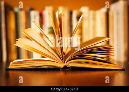 Livre relié laissés ouverts sur son couvercle avec les pages se déploient au-dessus de lui et d'une rangée de livres sur une étagère visible derrière, peu profonde 6 Banque D'Images