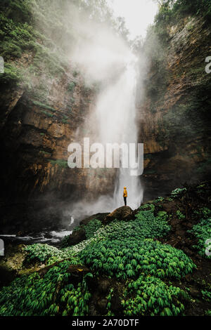 L'homme en Indonésie à la cascade au while sitting on rocks Banque D'Images