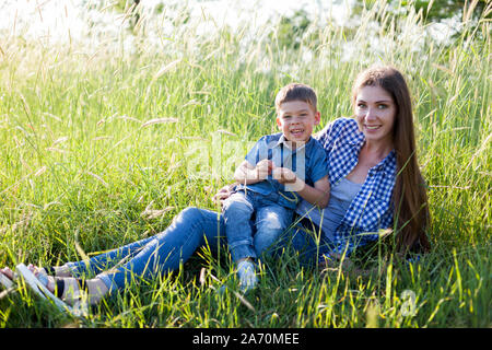 La maman et le petit fils se coucher sur l'herbe dans les bois Banque D'Images