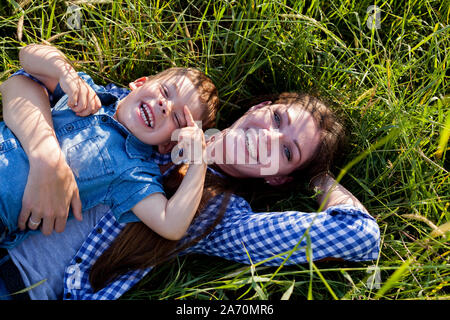 La maman et le petit fils se coucher sur l'herbe dans les bois Banque D'Images