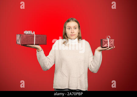 Une jeune femme tient deux cadeaux dans sa main et ne peut pas décider pour l'un Banque D'Images