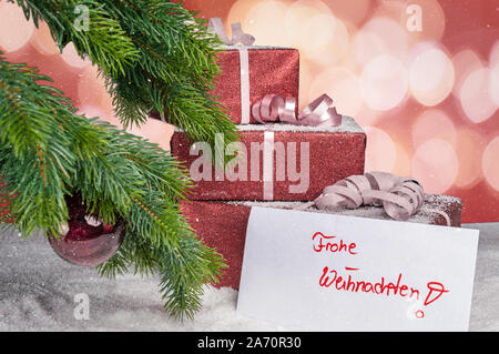 Des cadeaux de fête, se coucher sur une table avec une carte de vœux avec l'inscription joyeux noël en allemand Banque D'Images