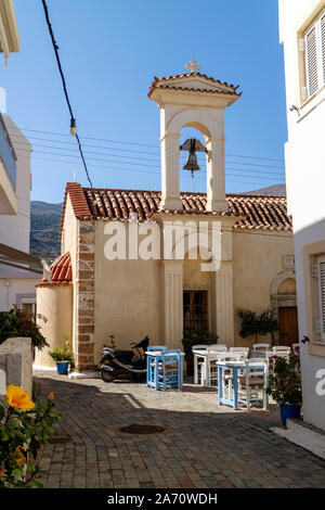 Malia, Crète, Grèce. Octobre 2019. Café et vieille église avec table et chaises au soleil situé dans la vieille ville de Malia, Crète Banque D'Images