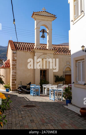 Malia, Crète, Grèce. Octobre 2019. Café et vieille église avec table et chaises au soleil situé dans la vieille ville de Malia, Crète Banque D'Images