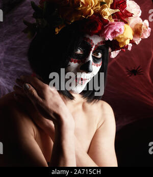 Belle fille avec masque de mort mexicain traditionnel. Calavera Catrina. Crâne en sucre. maquillage Fille habillée d'une guirlande de roses sur fond de blanc w Banque D'Images