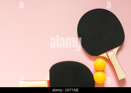 Raquettes de ping-pong tennis noir et orange balls isolé sur un fond rose, les équipements de sport pour tennis de table Banque D'Images