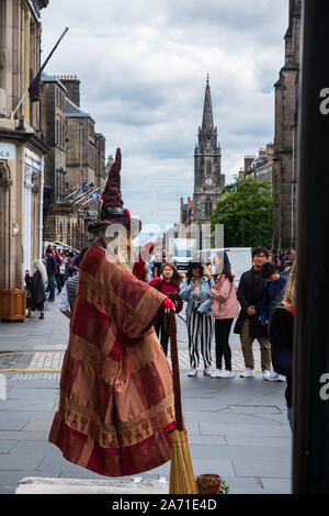 Edinburgh, Royaume-Uni - Juillet 5, 2019 : un artiste de rue sur le Royal Mile à Édimbourg vêtue comme une sorcière et tenant un balai semble flotter dans Banque D'Images