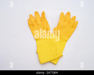 Gants en caoutchouc jaune vif sur un fond blanc tissu Banque D'Images