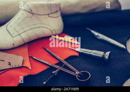 Outils d'artisanat du cuir sur fond de bois. Lieu de travail pour cordonnier. Morceau de cuir. Avec des outils de travail du cordonnier, cuir et chaussures en dernier. Petit shoem Banque D'Images