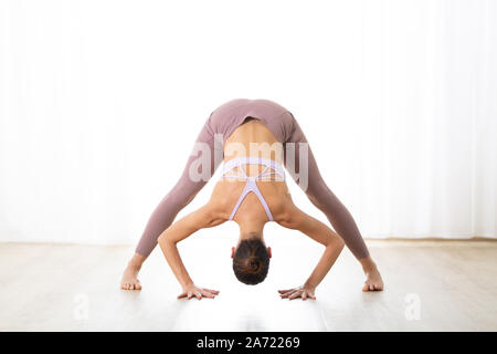 Portrait de jeune femme sportive active pratiquant le yoga en studio. Dandayamana Bibhaktapada pratique belle fille Paschimotthanasana Banque D'Images