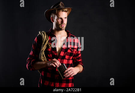 Monter un cheval rapide. cowboy avec lasso de corde. Chemise à carreaux homme. de l'ouest sur ranch. et de l'ouest portrait. L'homme de style vintage. Wild West cow-boy rétro. wild west rodeo. man in hat fond noir. Banque D'Images