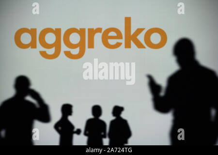 Le logo d'Aggreko est vu sur un écran LED à l'arrière-plan tandis qu'une silhouette personne utilise un smartphone (usage éditorial uniquement) Banque D'Images