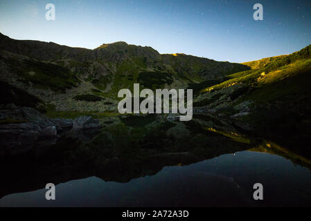 Lune n'illumine la nuit Paysage de crête et reflétant dans l'eau cristalline du lac alpin - Tarn, Parc National des Basses Tatras, Slovaquie Banque D'Images