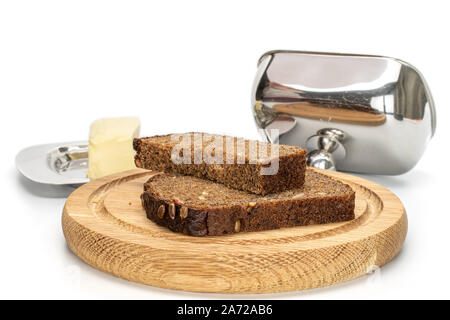 Groupe de deux tranches de pain frais cuit sur plaque bambou foncé avec beurrier isolé sur fond blanc Banque D'Images