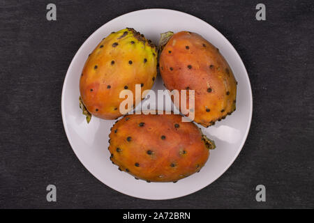 Groupe de trois entiers et frais d'Opuntia orange blanc sur plaque de céramique sur flatlay pierre gris Banque D'Images