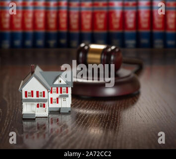 Marteau et petit modèle Maison sur table en bois avec livres de droit en arrière-plan. Banque D'Images