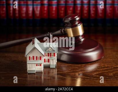 Marteau et petit modèle Maison sur table en bois avec livres de droit en arrière-plan. Banque D'Images