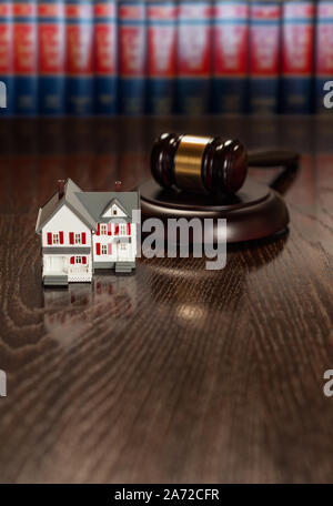 Marteau et petit modèle Maison sur table en bois avec livres de droit en arrière-plan. Banque D'Images