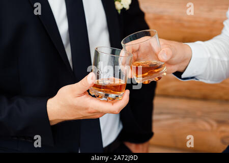 Deux verres de whisky dans les mains des hommes. L'alcool. La célébration. Banque D'Images
