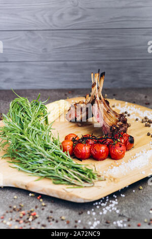 Côtes de la viande avec des légumes sur une planche en bois avec des herbes. Banque D'Images