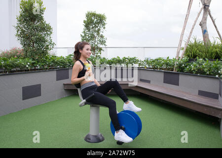 Femme exerçant avec appareils d'exercice dans le parc public avec bouteille d'eau dans la main de detox Banque D'Images