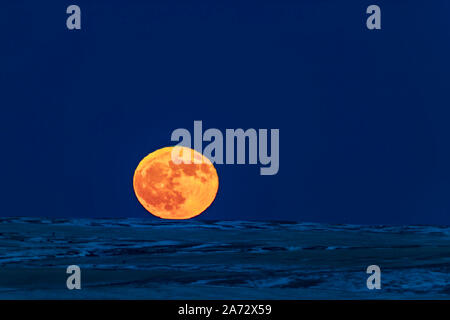 La Pleine Lune rising le 22 décembre 2018, le jour après le solstice d'hiver, dans un ciel parfaitement clair et plus loin à l'horizon pour le nord-est Banque D'Images