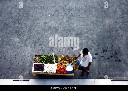 ANTIPOLO CITY, PHILIPPINES - 25 octobre 2019 : vendeur vend Fruits Fruits frais assortis dans son panier alimentaire et attend les clients à un trottoir. Banque D'Images